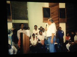 Photo of Paul Kittlaus speaking at the church in El Bosque on Pentecost Sunday. He speaks in English. The indigenous people speak Tojolabal, a Mayan dialect. A quick survey does not find a person who can translate English into Tojolabal. A Dutch missionary can translate English to Spanish, neither his native language. Someone else can translate Spanish into Tojolabol. So we created a system that gives us promise that what he says is what they will hear. He spoke slowly pausing often for two translations to occur. No one was able to estimate the degree of accuracy between the English and the Tojolabal. (1998)